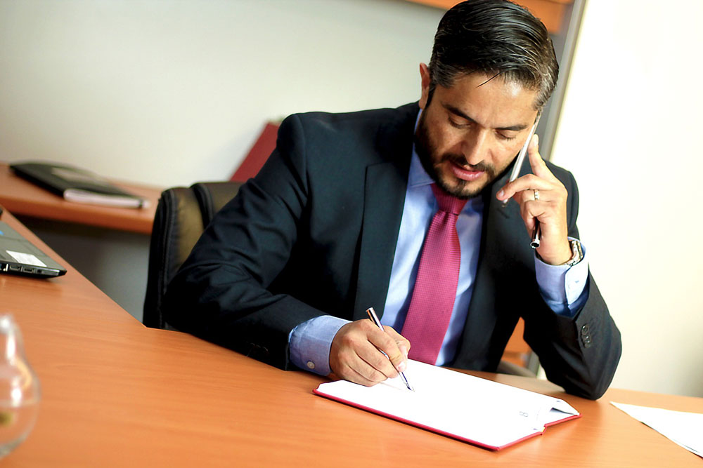 Attorney talking on the phone while writing in a datebook.