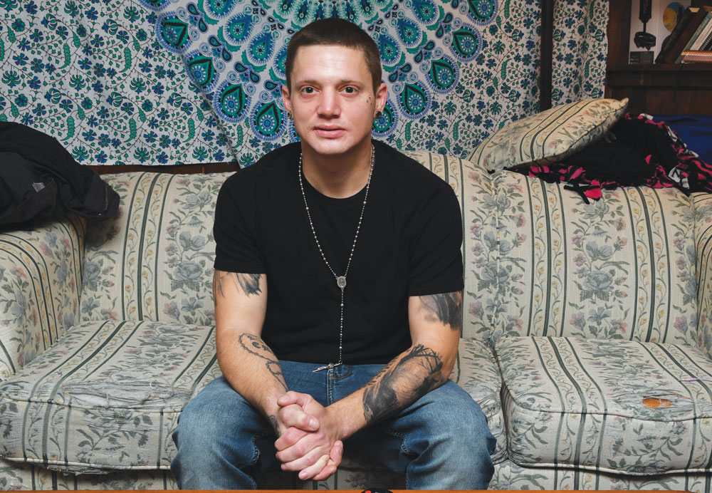 In and out of jail and rehab for 13 years, Benjamin Bryant sitting on a couch, hands clasped in his lap looking straight ahead.