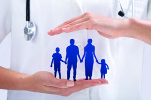 Close-up Of Doctor's Hand Protecting The Blue Family Paper Cut Out